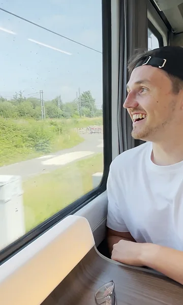 A smiling passenger sitting beside a train window